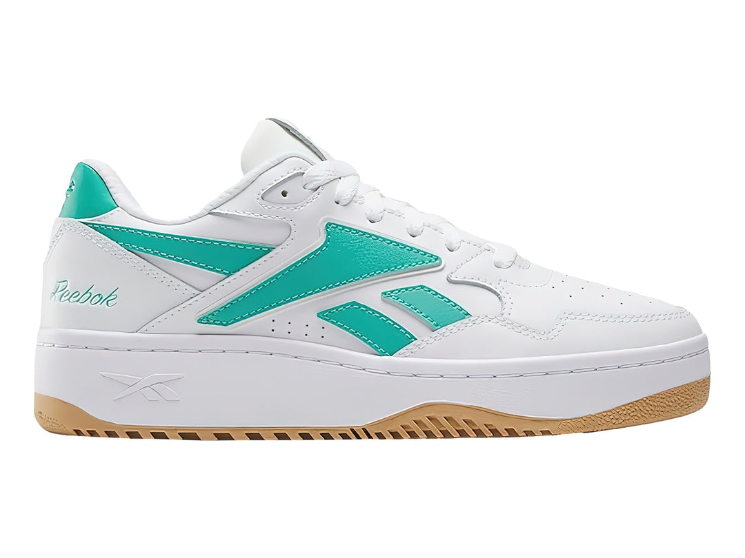 Tenis Reebok blancos con detalles en verde y suela de goma color miel.