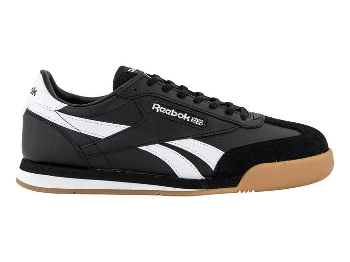 Tenis Reebok negros con franjas blancas y suela de goma color miel.