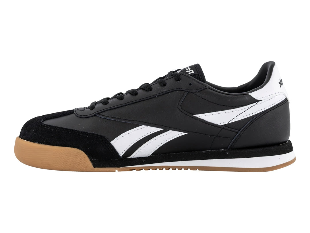 Tenis Reebok negros con franjas blancas y suela de goma color miel.