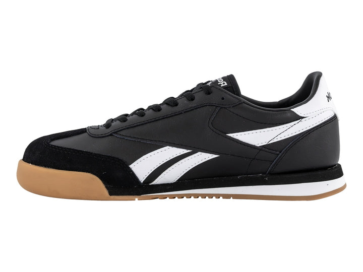 Tenis Reebok negros con franjas blancas y suela de goma color miel.