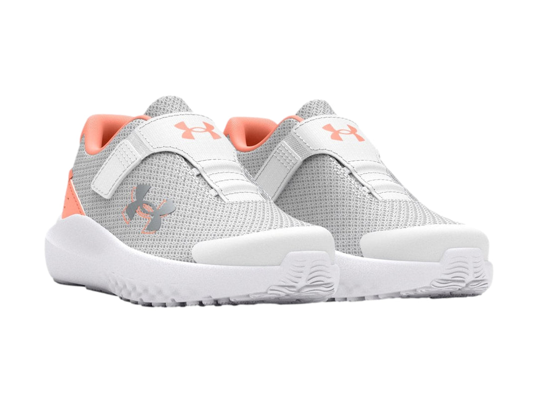 Tenis deportivos Under Armour color gris con suela blanca y detalles en naranja.