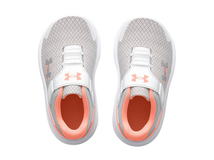 Tenis deportivos Under Armour color gris con suela blanca y detalles en naranja.