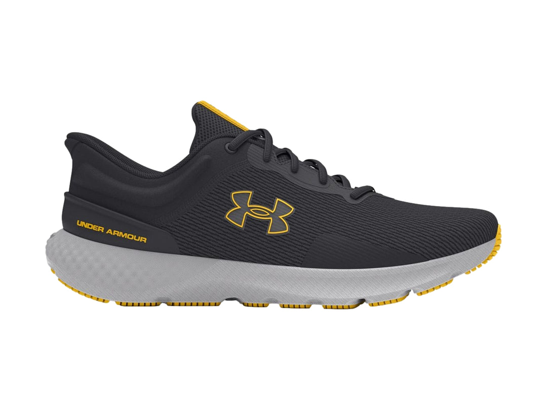 Tenis deportivos Under Armour color gris con suela clara y detalles en amarillo.