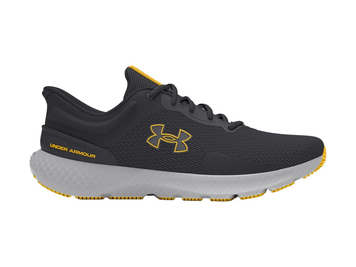 Tenis deportivos Under Armour color gris con suela clara y detalles en amarillo.