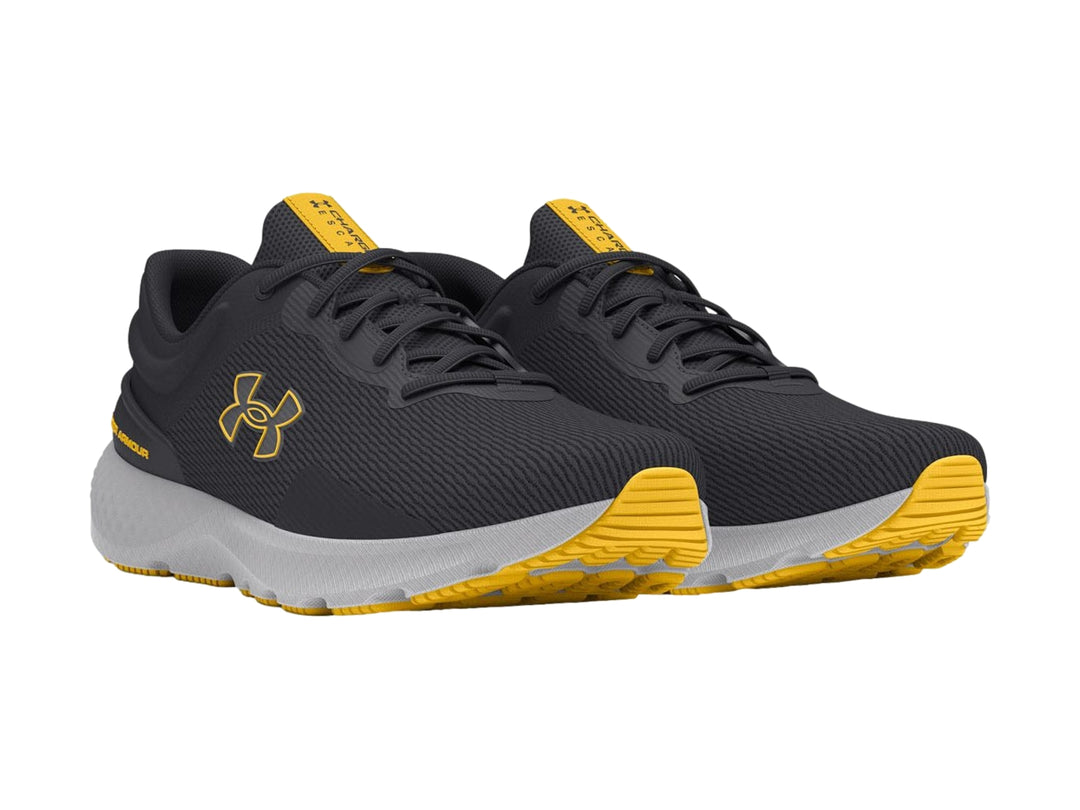Tenis deportivos Under Armour color gris con suela clara y detalles en amarillo.