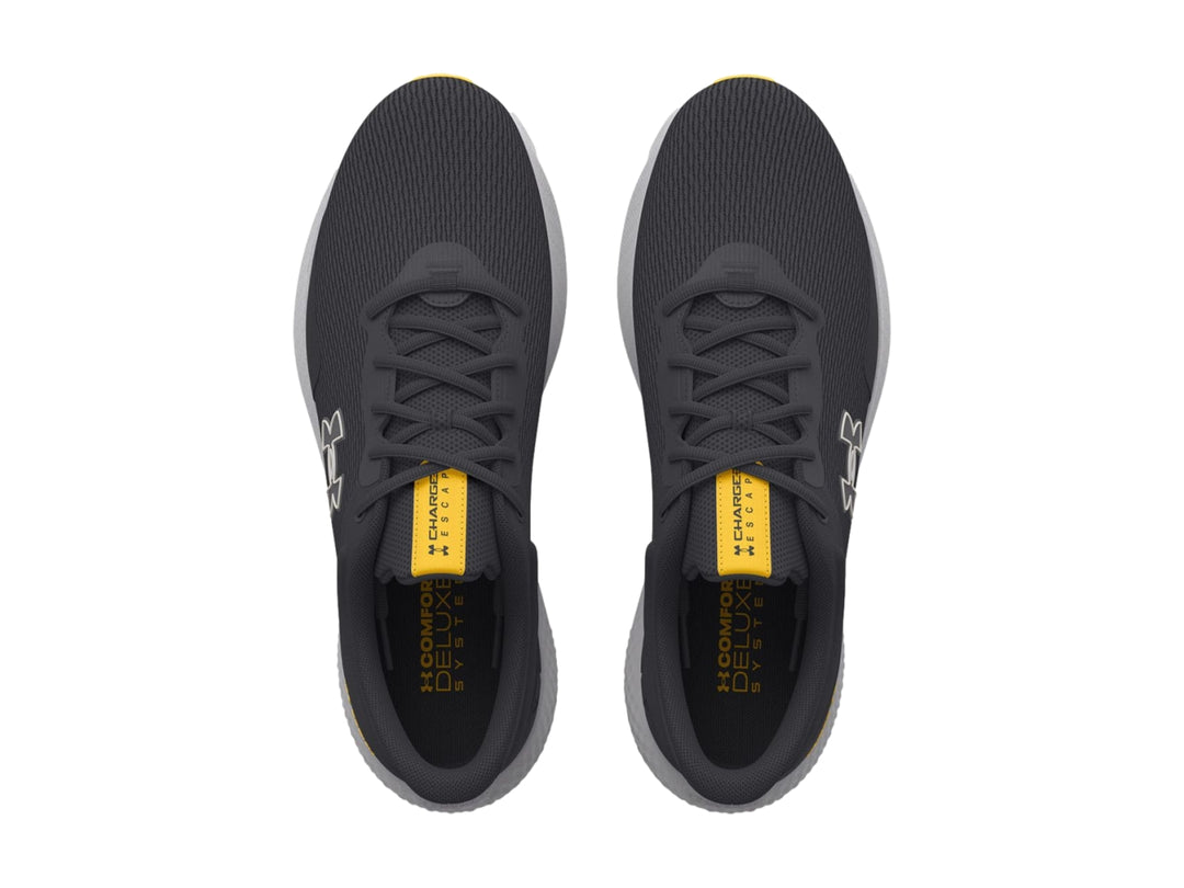 Tenis deportivos Under Armour color gris con suela clara y detalles en amarillo.