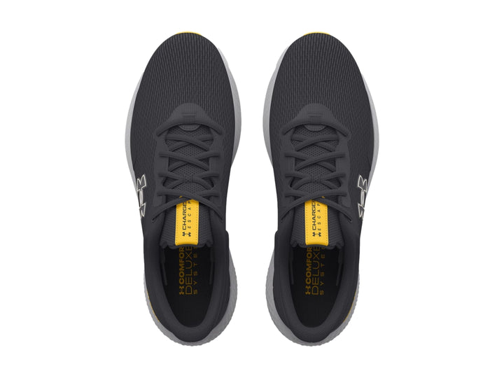Tenis deportivos Under Armour color gris con suela clara y detalles en amarillo.