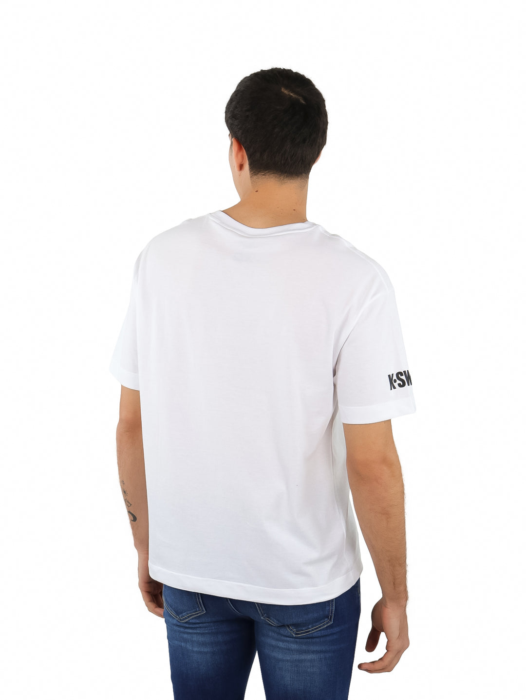 Hombre vistiendo playera blanca de manga corta K-Swiss con estampados laterales y logo en el pecho.