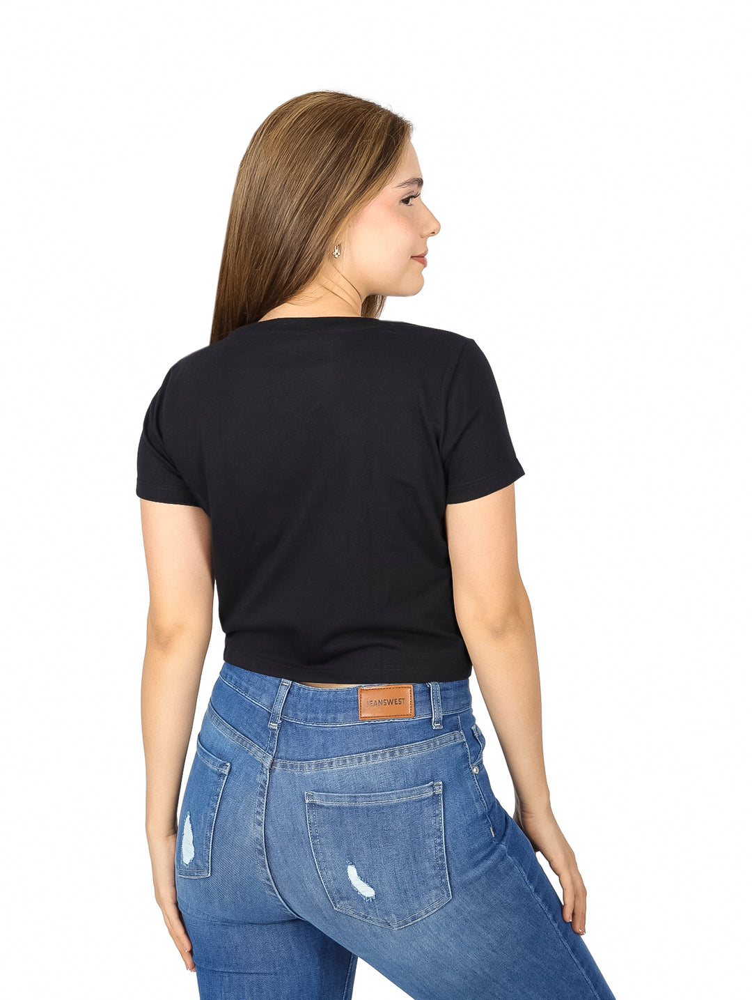 Mujer vistiendo una playera corta negra de marca K-SWISS con logotipo frontal y pantalones de mezclilla azules.