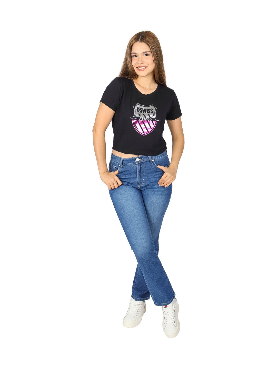 Mujer vistiendo una playera corta negra de marca K-SWISS con logotipo frontal y pantalones de mezclilla azules.
