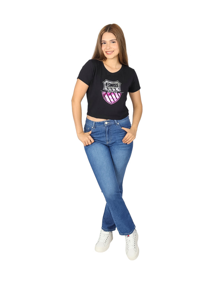 Mujer vistiendo una playera corta negra de marca K-SWISS con logotipo frontal y pantalones de mezclilla azules.