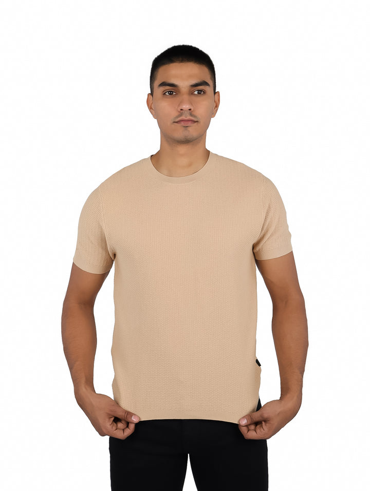 Hombre vistiendo una playera color beige de manga corta y cuello redondo.