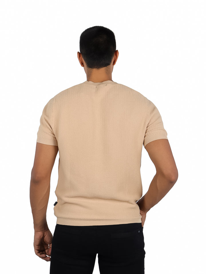 Hombre vistiendo una playera color beige de manga corta y cuello redondo.