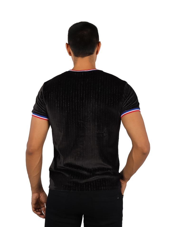 Hombre vistiendo playera negra de manga corta con detalles tricolores en cuello y mangas.