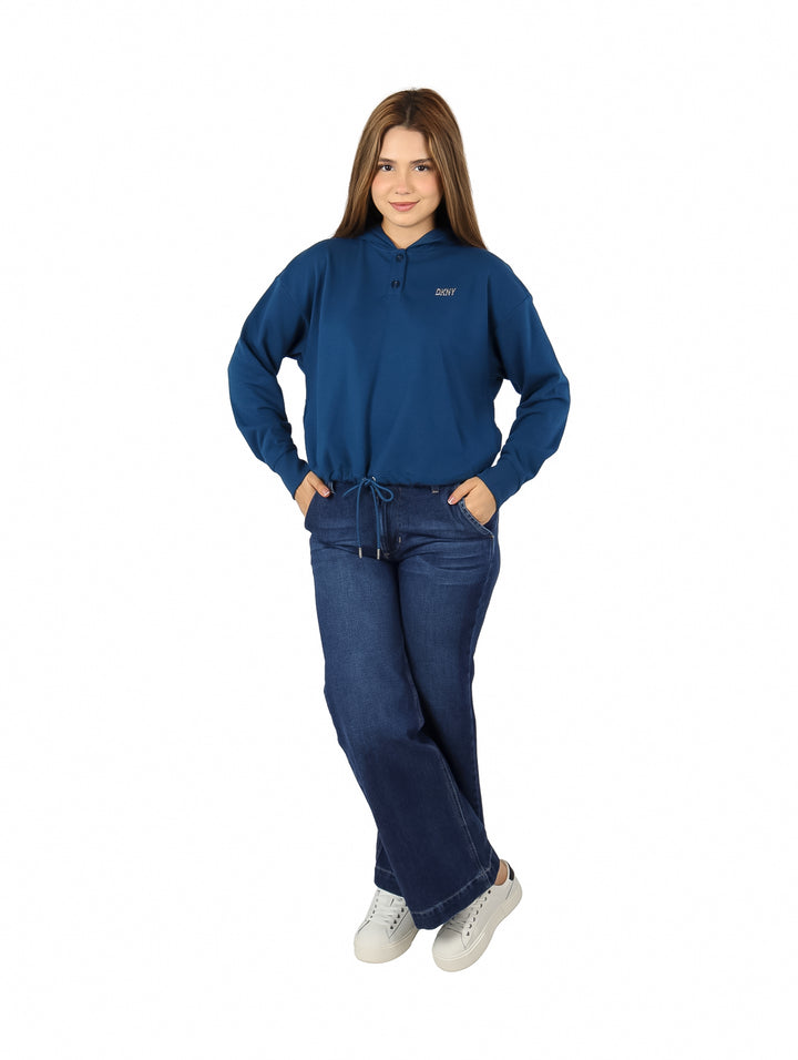 Mujer vistiendo una sudadera azul DKNY con capucha y pantalones de mezclilla.