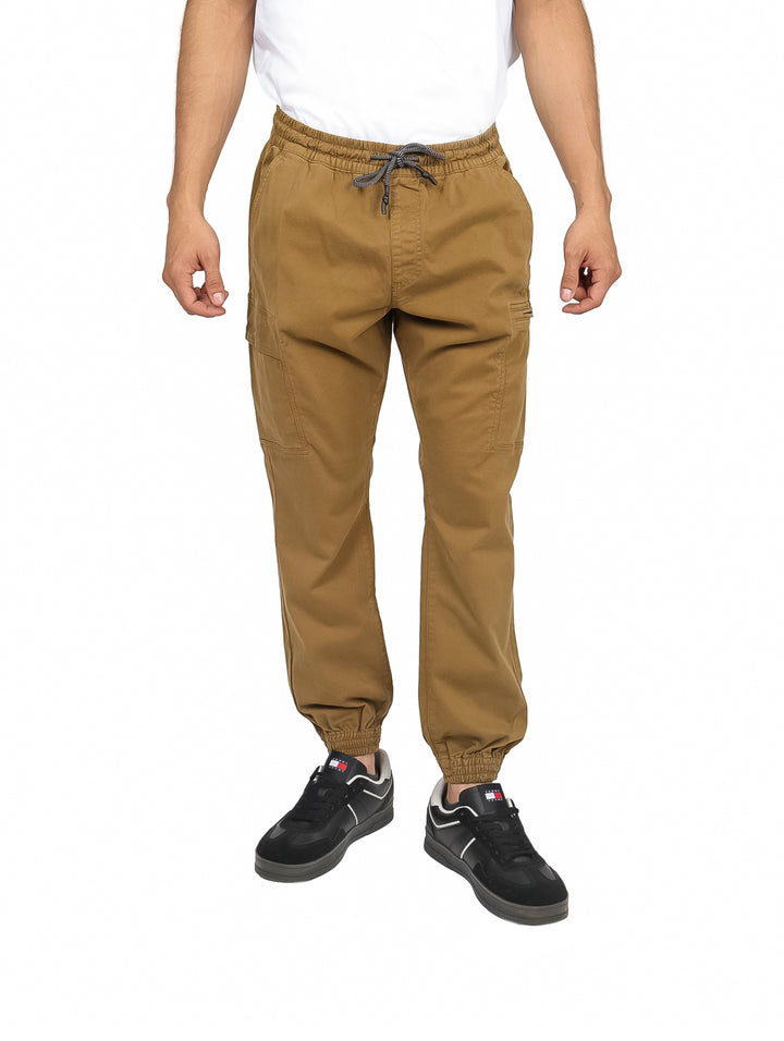 Hombre vistiendo pantalones jogger color mostaza con cintura ajustable y puños elásticos.