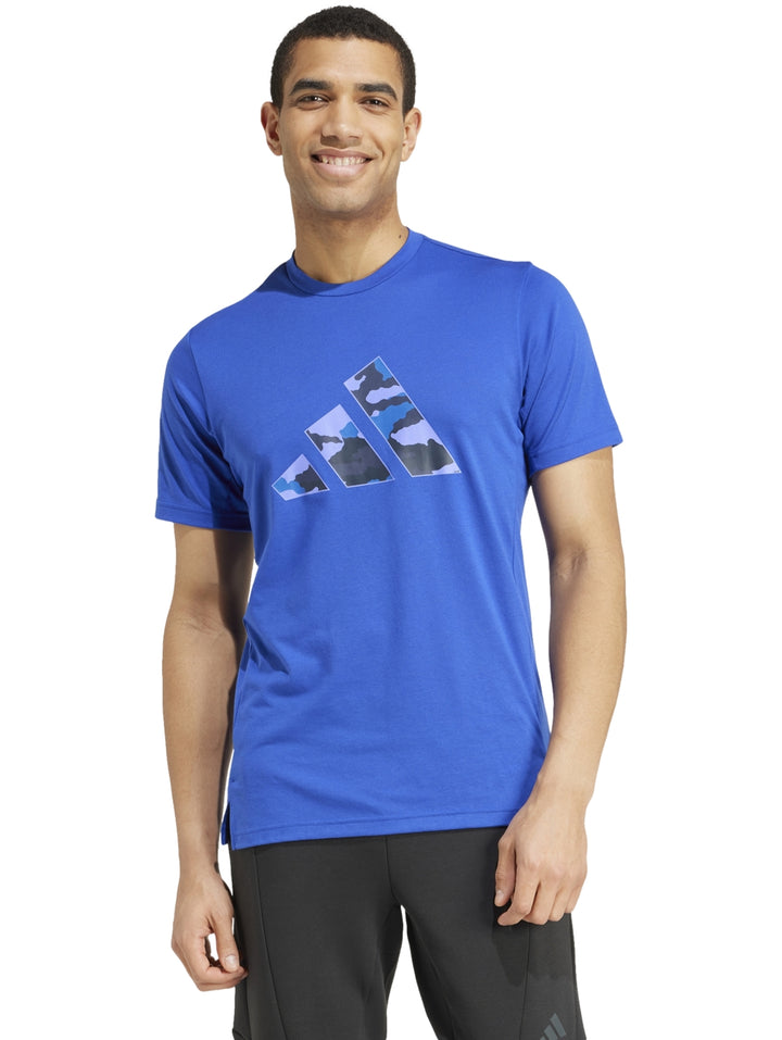 Hombre vistiendo playera Adidas color azul semi lucid blue con logotipo gráfico de camuflaje en el pecho.