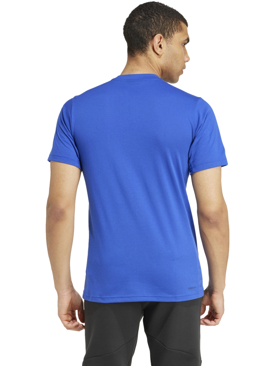 Hombre vistiendo playera Adidas color azul semi lucid blue con logotipo gráfico de camuflaje en el pecho.