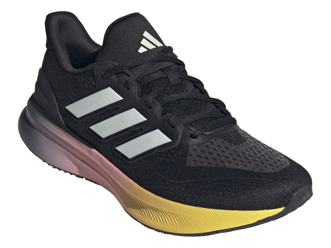Tenis deportivos Adidas color negro con suela en degradado de rosa a amarillo y franjas blancas laterales.