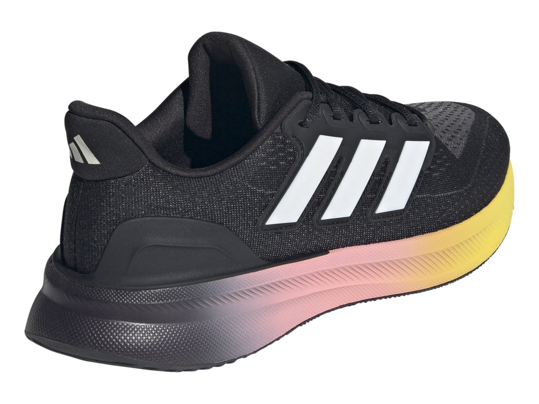 Tenis deportivos Adidas color negro con suela en degradado de rosa a amarillo y franjas blancas laterales.
