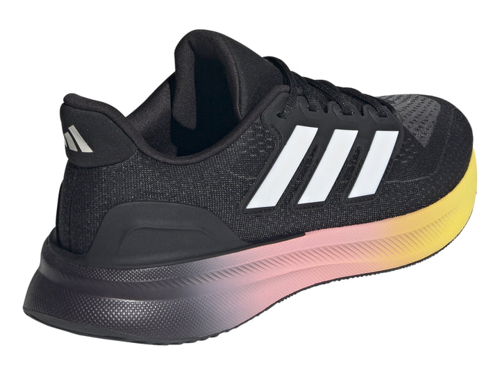 Tenis deportivos Adidas color negro con suela en degradado de rosa a amarillo y franjas blancas laterales.