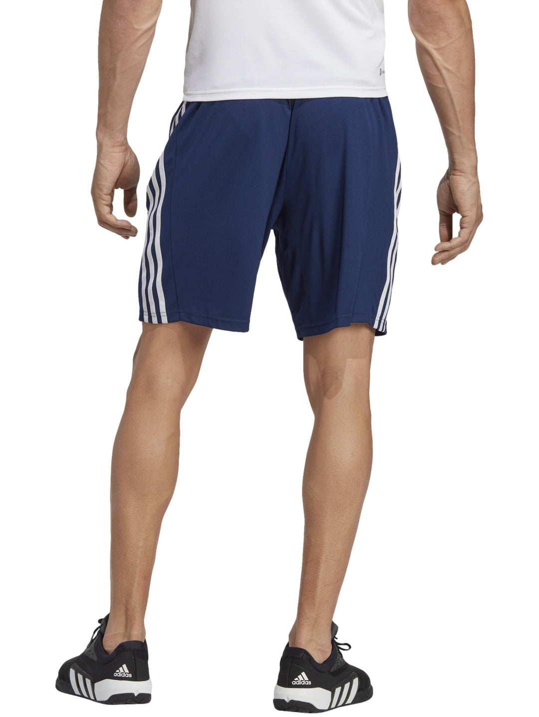 Hombre usando shorts deportivos Adidas azul oscuro con franjas blancas laterales.