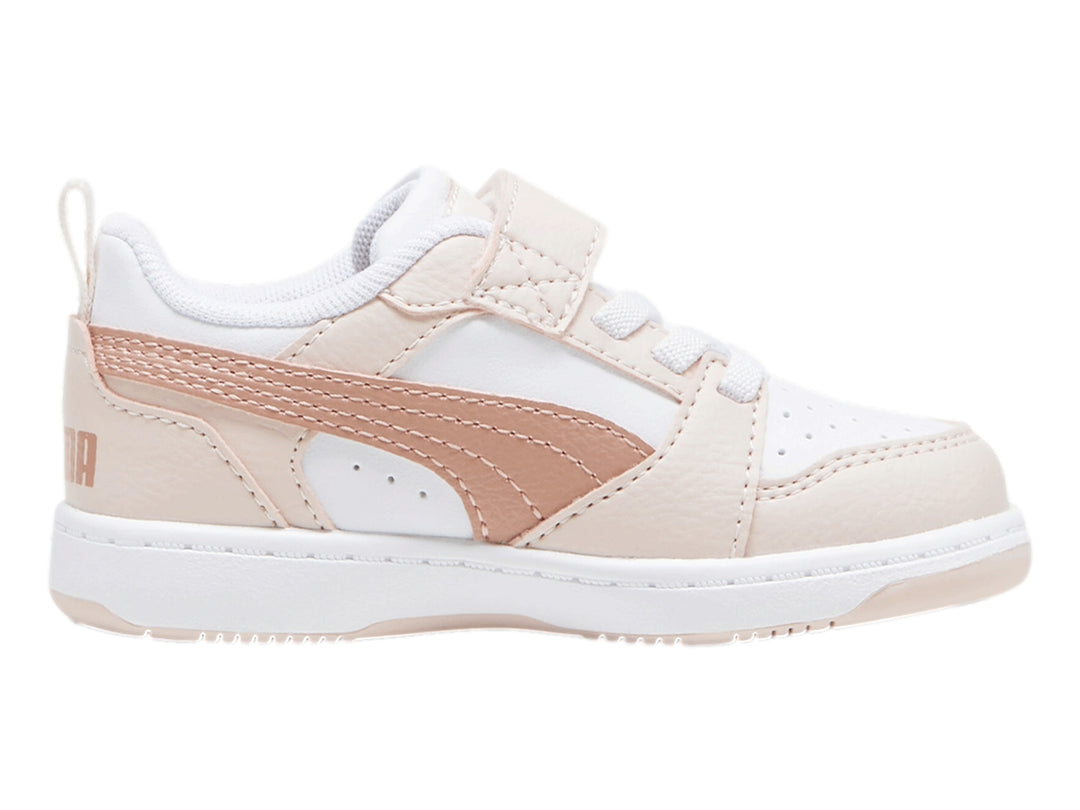Tenis PUMA Rebound V6 Lo AC+ Infant en color blanco con detalles en rosa pastel y cierre de velcro.