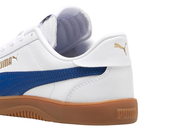 Tenis PUMA blancos con franja azul y suela color café para niños.
