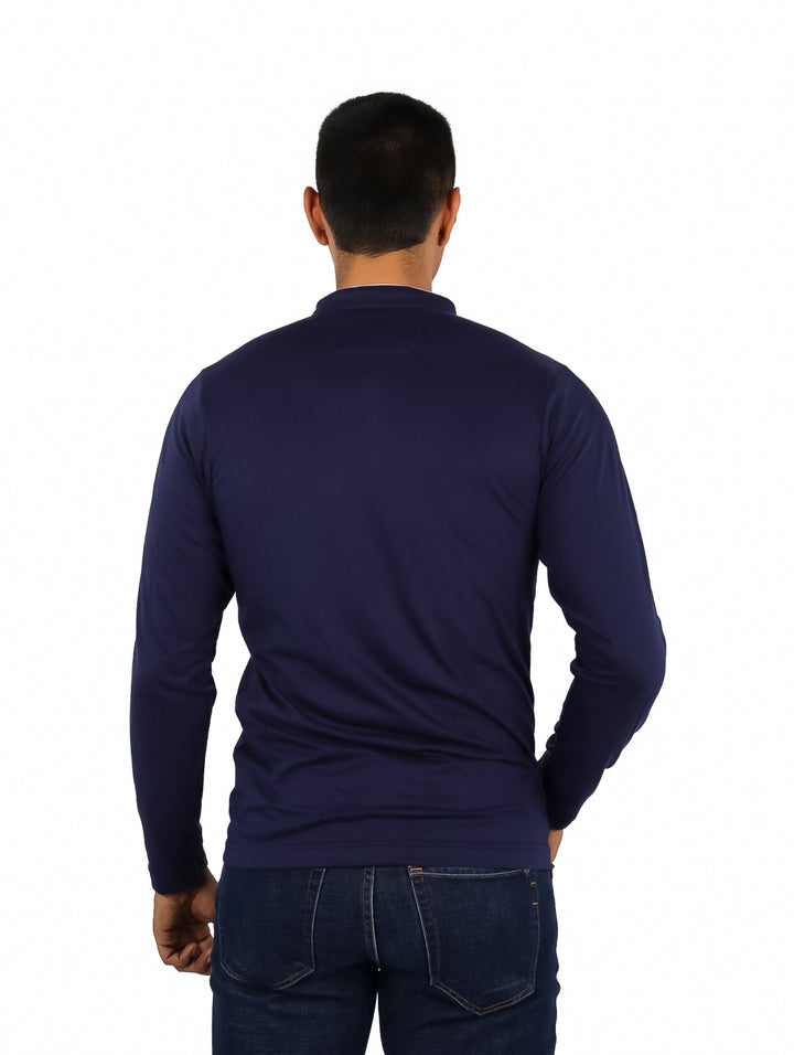 Hombre vistiendo playera polo de manga larga color azul marino con detalles blancos en el cuello y bolsillo.