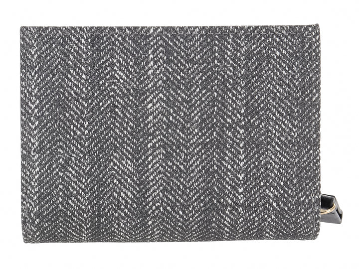 Monedero rectangular de tela con estampado de espiga en colores negro y gris y placa metálica central.