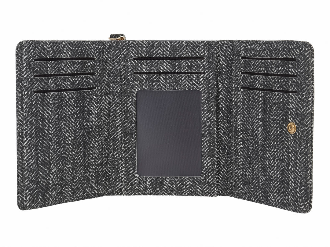 Monedero rectangular de tela con patrón de espiga en colores negro y gris y un detalle metálico frontal.