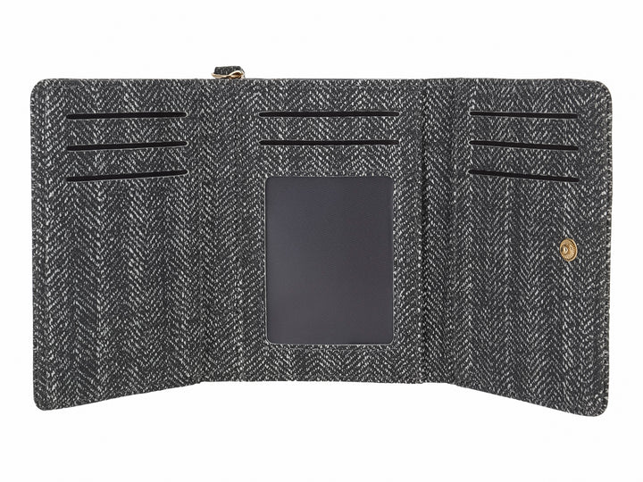 Monedero rectangular de tela con patrón de espiga en colores negro y gris y un detalle metálico frontal.