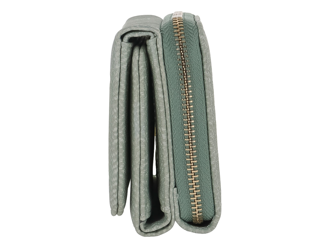 Monedero compacto de color verde con textura en patrón de espiga y placa metálica dorada frontal.