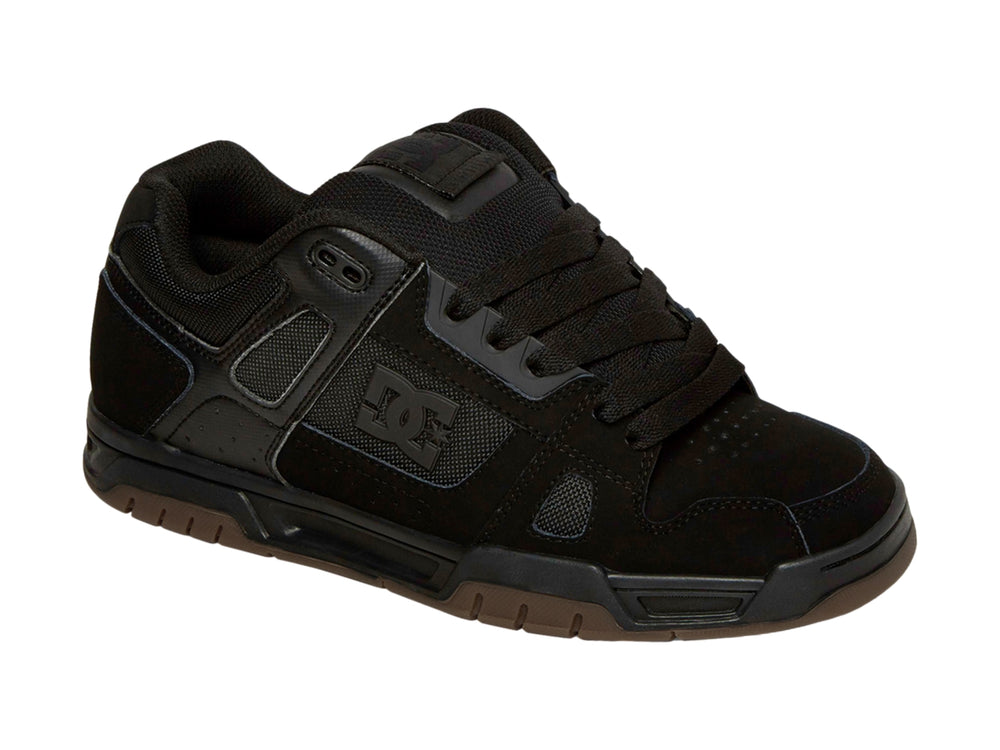 Tenis DC Shoes color negro con suela de goma marrón, diseño deportivo para skate.