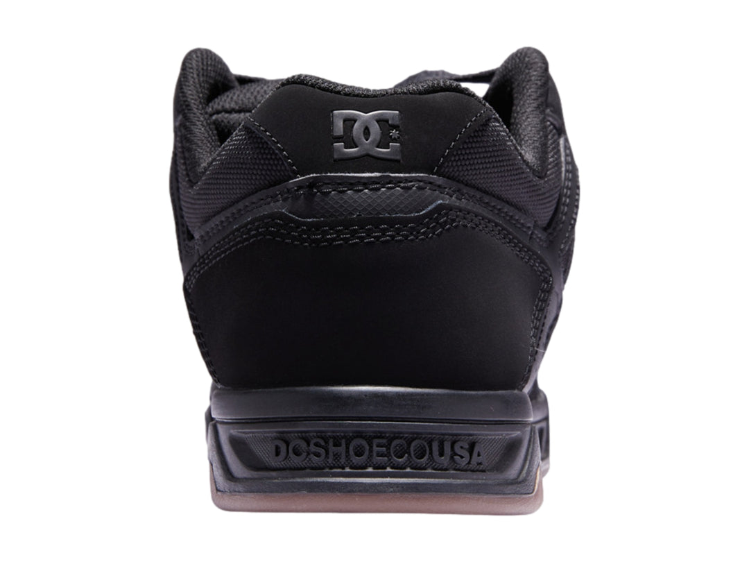 Tenis DC Shoes color negro con suela de goma marrón, diseño deportivo para skate.