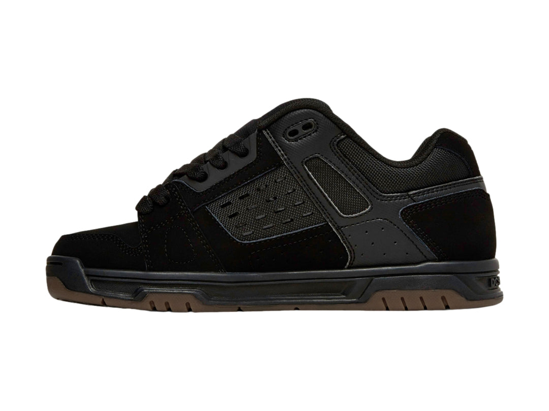 Tenis DC Shoes color negro con suela de goma marrón, diseño deportivo para skate.