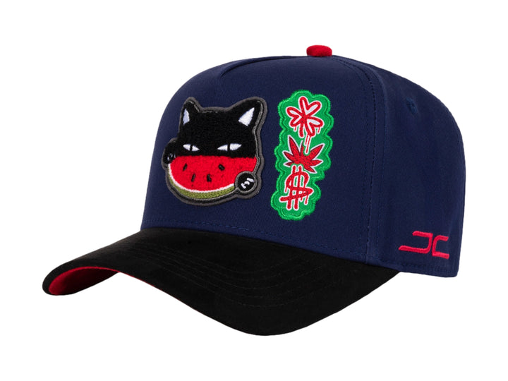 Gorra snapback azul con visera negra y parches decorativos de gato sandía y diseño floral.