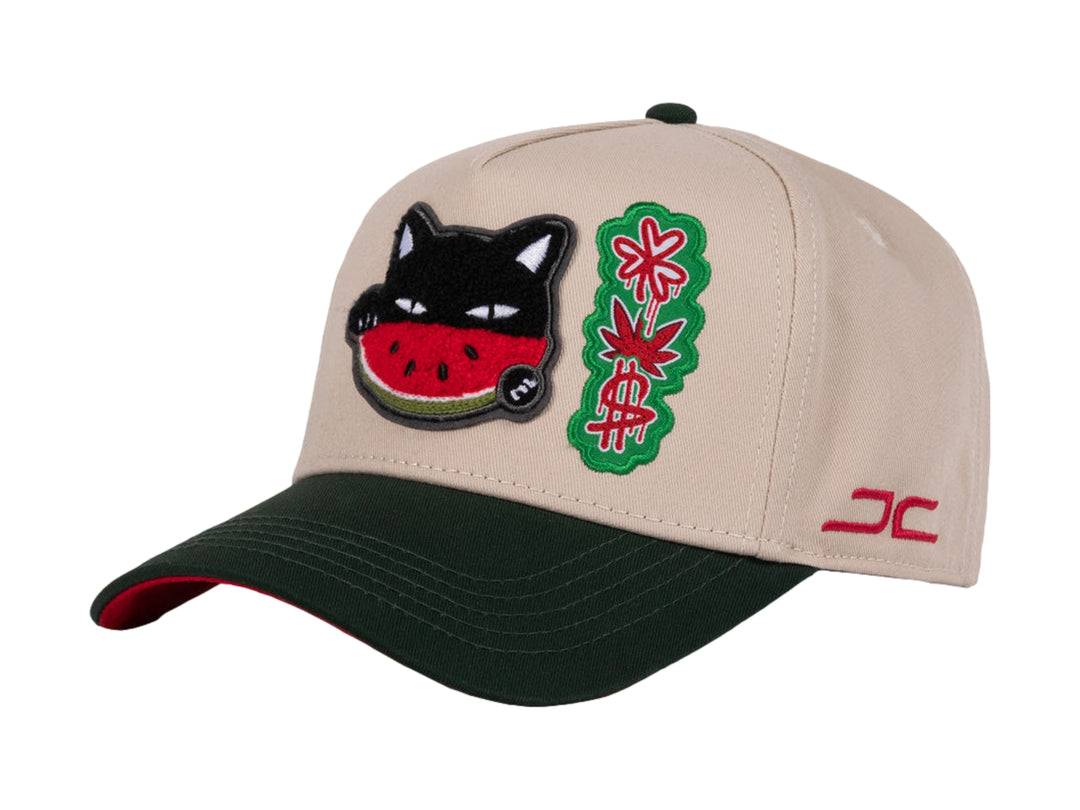 Gorra snapback color beige con visera verde y un parche bordado de un gato comiendo sandía en el frente.