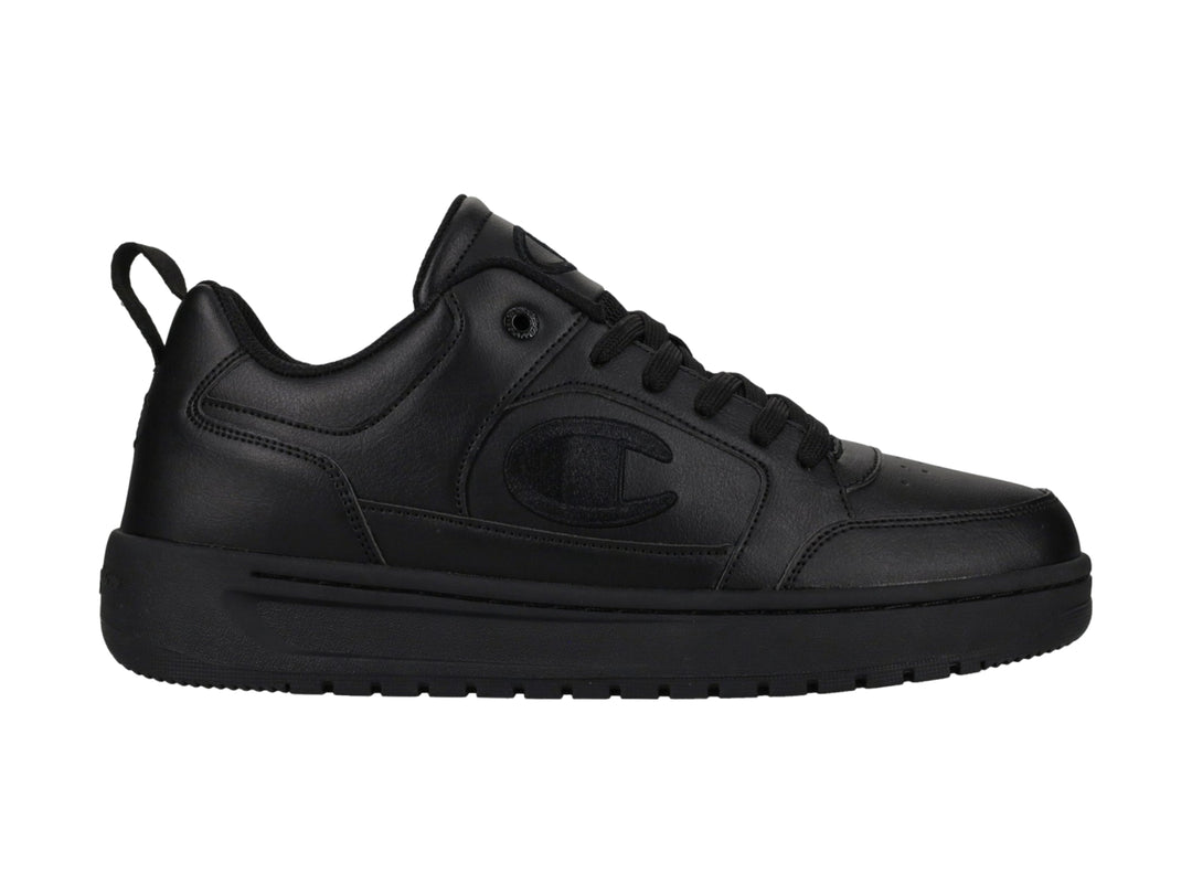 Tenis Champion color negro, diseño de corte bajo con suela gruesa y logo en el lateral.