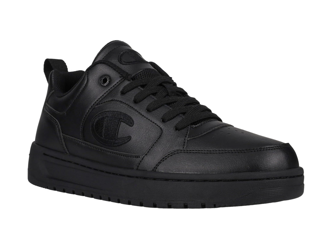 Tenis Champion color negro, diseño de corte bajo con suela gruesa y logo en el lateral.