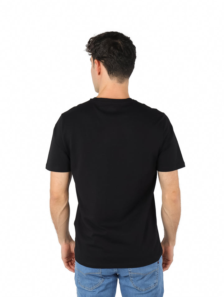Hombre vistiendo una camiseta negra de manga corta con estampado gráfico de DKNY en el pecho.