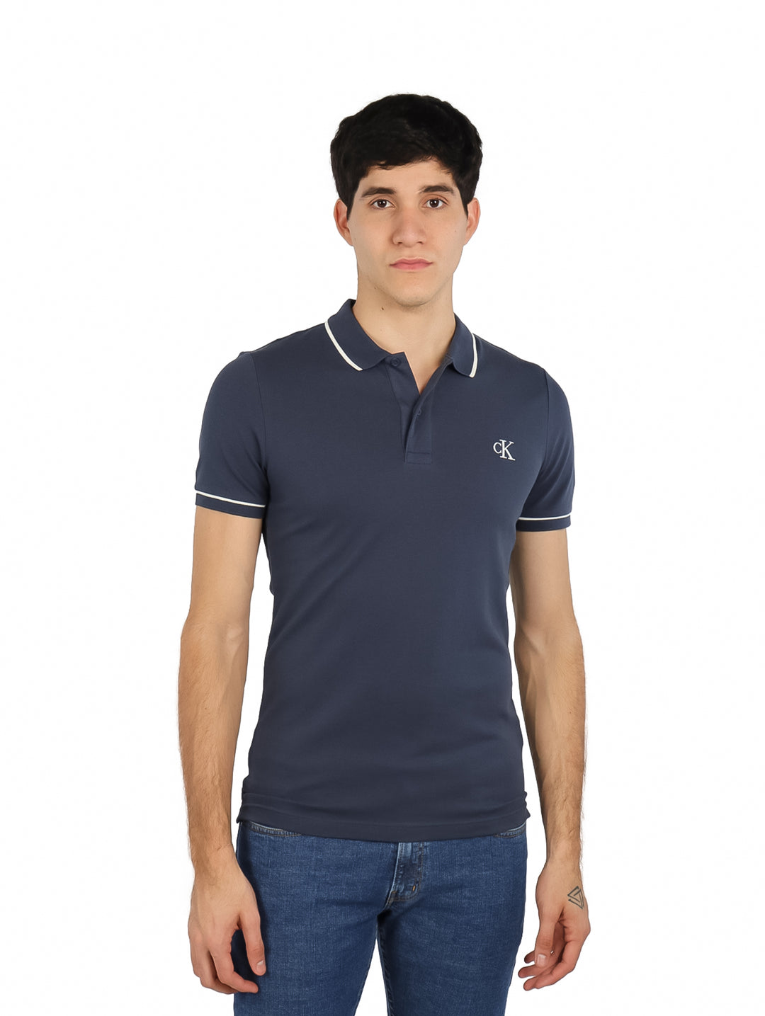 Hombre vistiendo una camiseta polo azul marino de Calvin Klein con detalles blancos en el cuello y mangas.