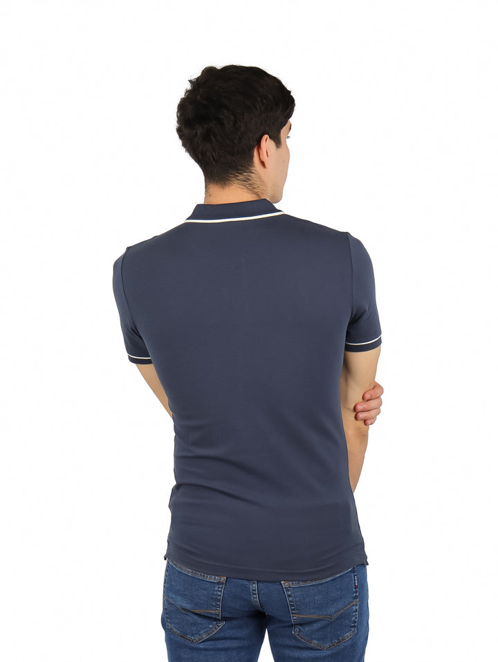 Hombre vistiendo una camiseta polo azul marino de Calvin Klein con detalles blancos en el cuello y mangas.