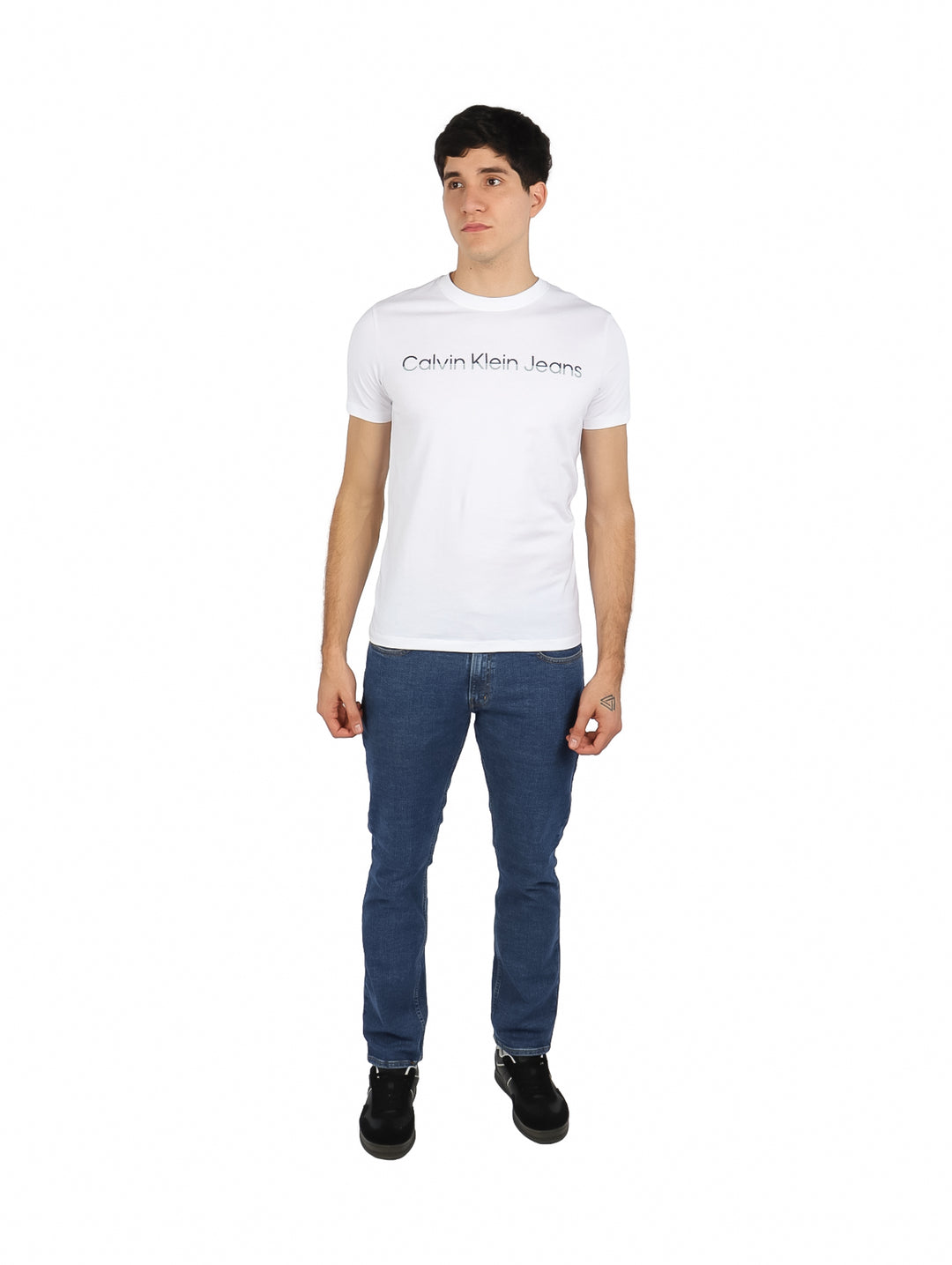 Hombre vistiendo playera blanca de cuello redondo con logotipo de Calvin Klein Jeans en el pecho.