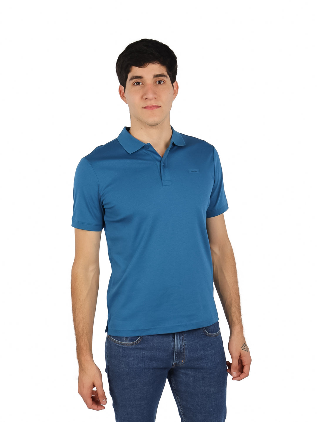 Hombre vistiendo una playera polo azul de manga corta de la marca Calvin Klein.
