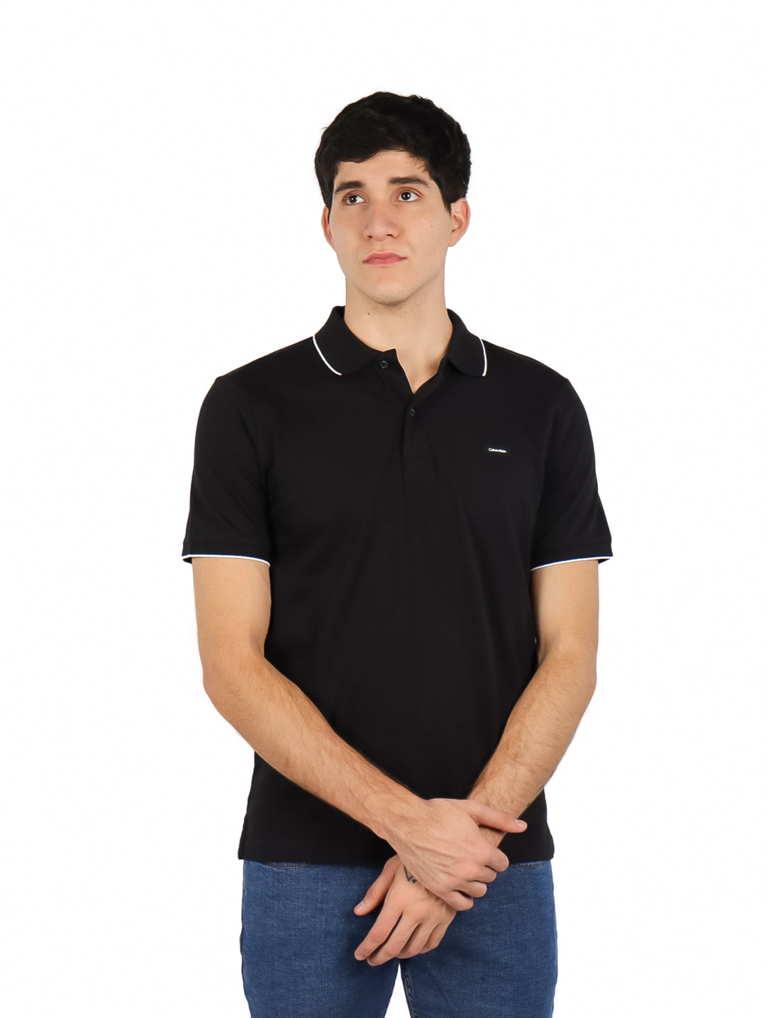 Hombre vistiendo polo negro de Calvin Klein con detalles blancos en cuello y mangas.