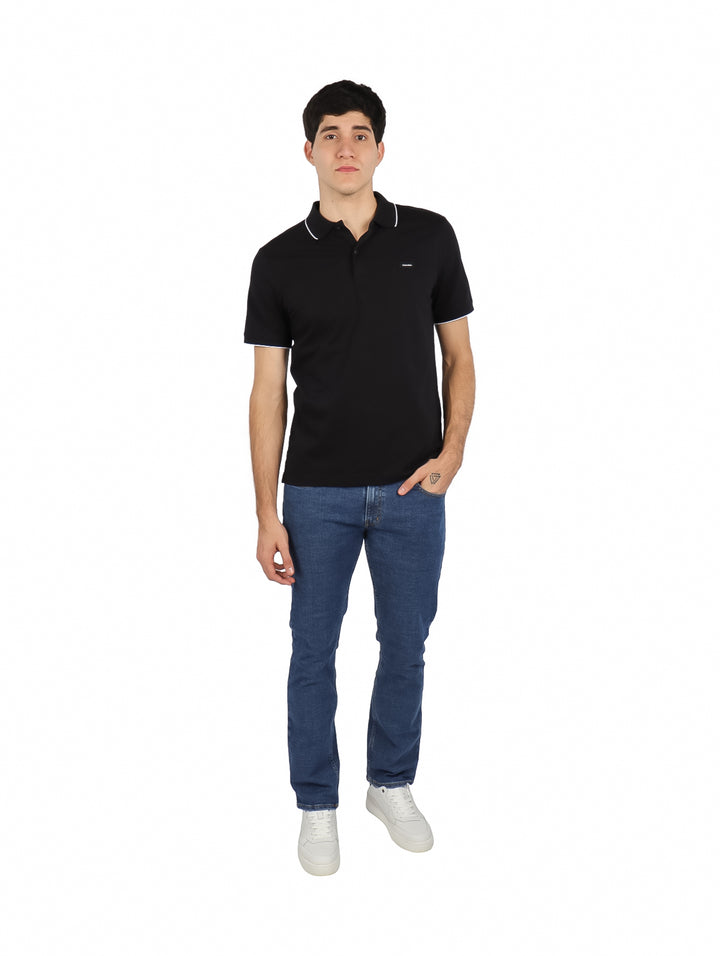 Hombre vistiendo polo negro de Calvin Klein con detalles blancos en cuello y mangas.