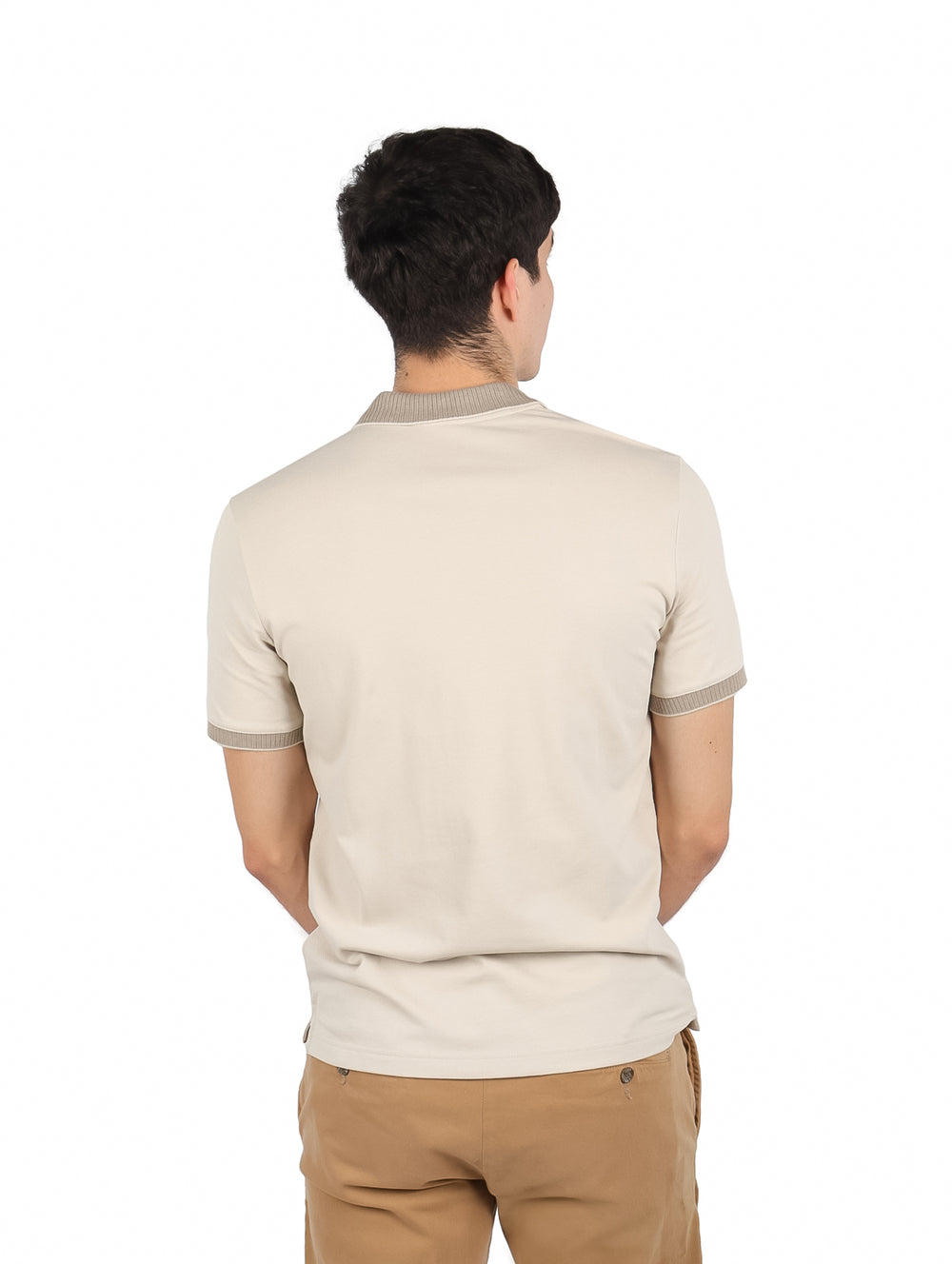 Hombre vistiendo playera polo color beige de Calvin Klein con pantalones color café claro.