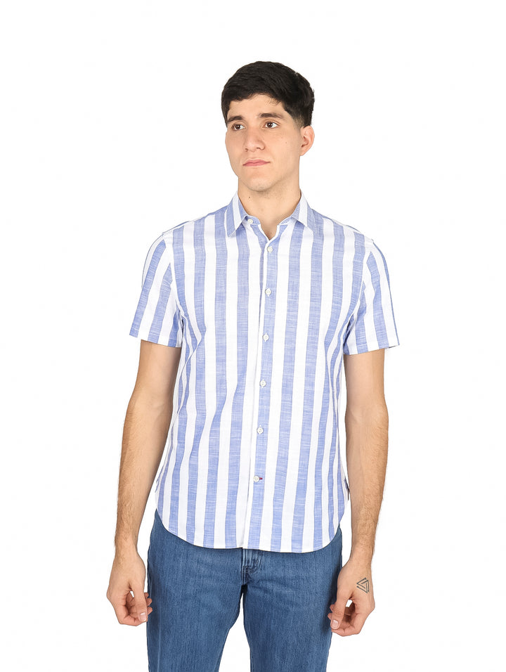 Hombre vistiendo camisa de manga corta con rayas verticales azules y blancas, estilo casual.