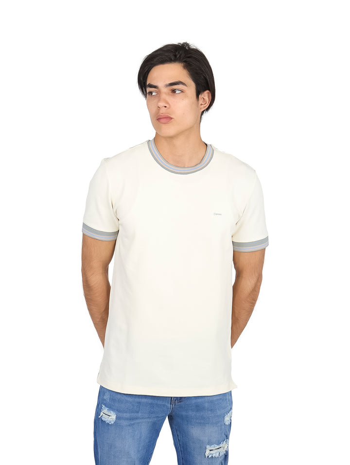 Hombre vistiendo playera color off white con ribetes grises en el cuello y los bordes de las mangas.